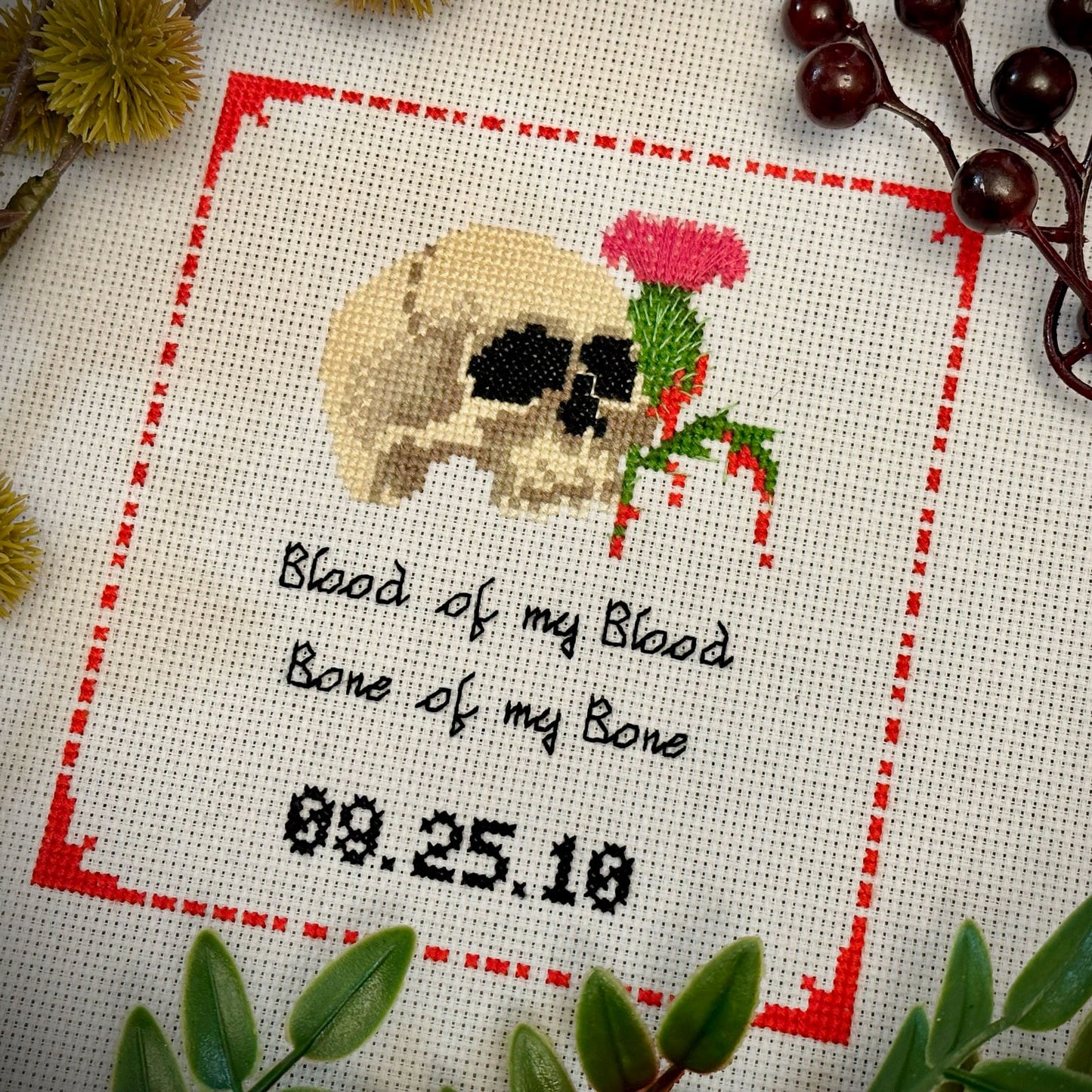 Human Skull with blood dripping from a Scottish thistle, cursive text that says Blood of my Blood, Bone of my Bone with the anniversary date centered below it.